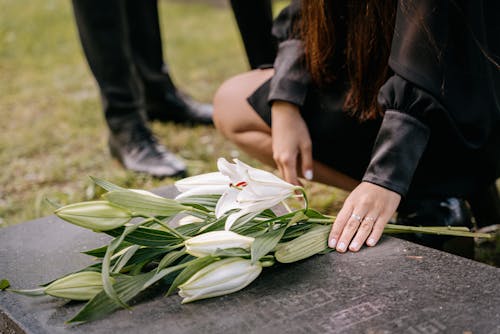 Free Woman in Black Clothes Holding White Flowers on Grave Stock Photo